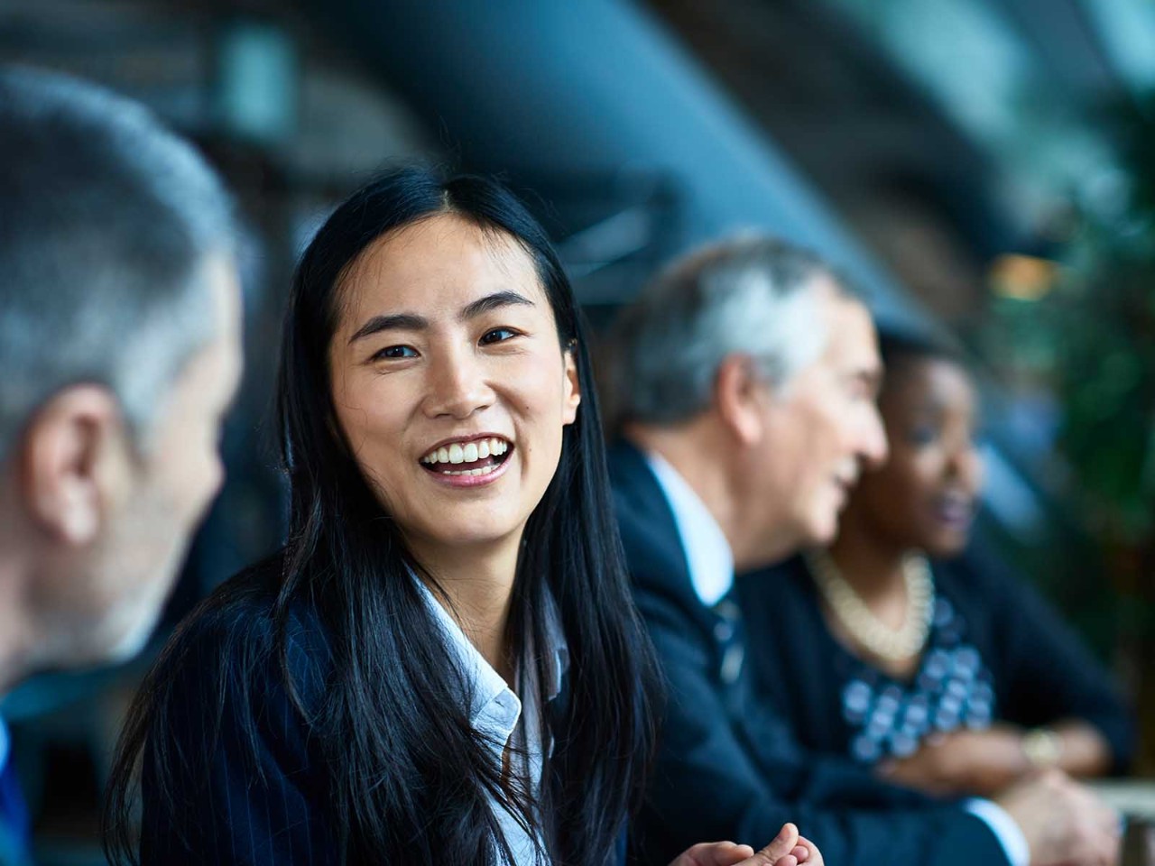 Close up portrait of Asian businesswoman, beside male senior coworker, smiling and laughing, respect, admiration